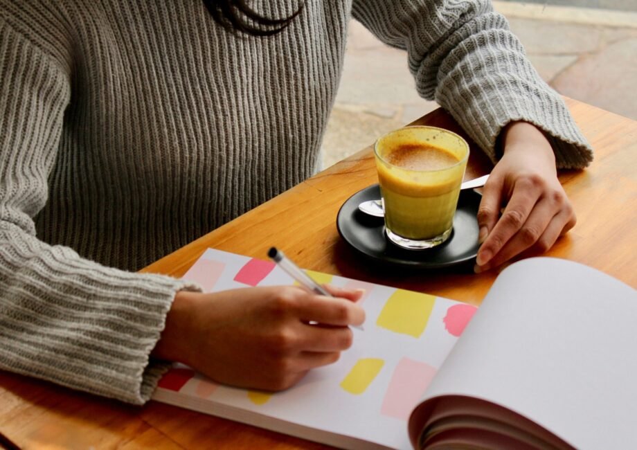 person holding pen with coffee on table