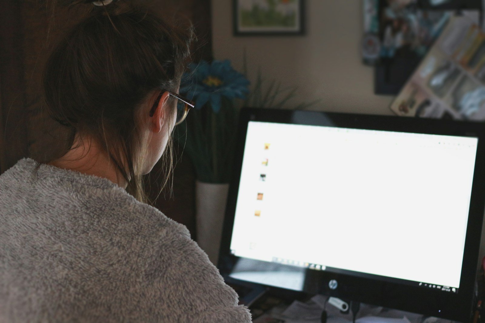 Mulher feliz trabalhando em casa no notebook com produtos ao redor para renda extra em 2025