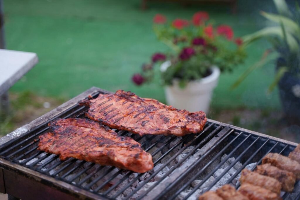 Juicy ribs sizzling on a charcoal grill in a garden setting. Perfect for summer BBQs.