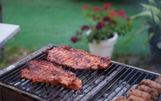 Juicy ribs sizzling on a charcoal grill in a garden setting. Perfect for summer BBQs.