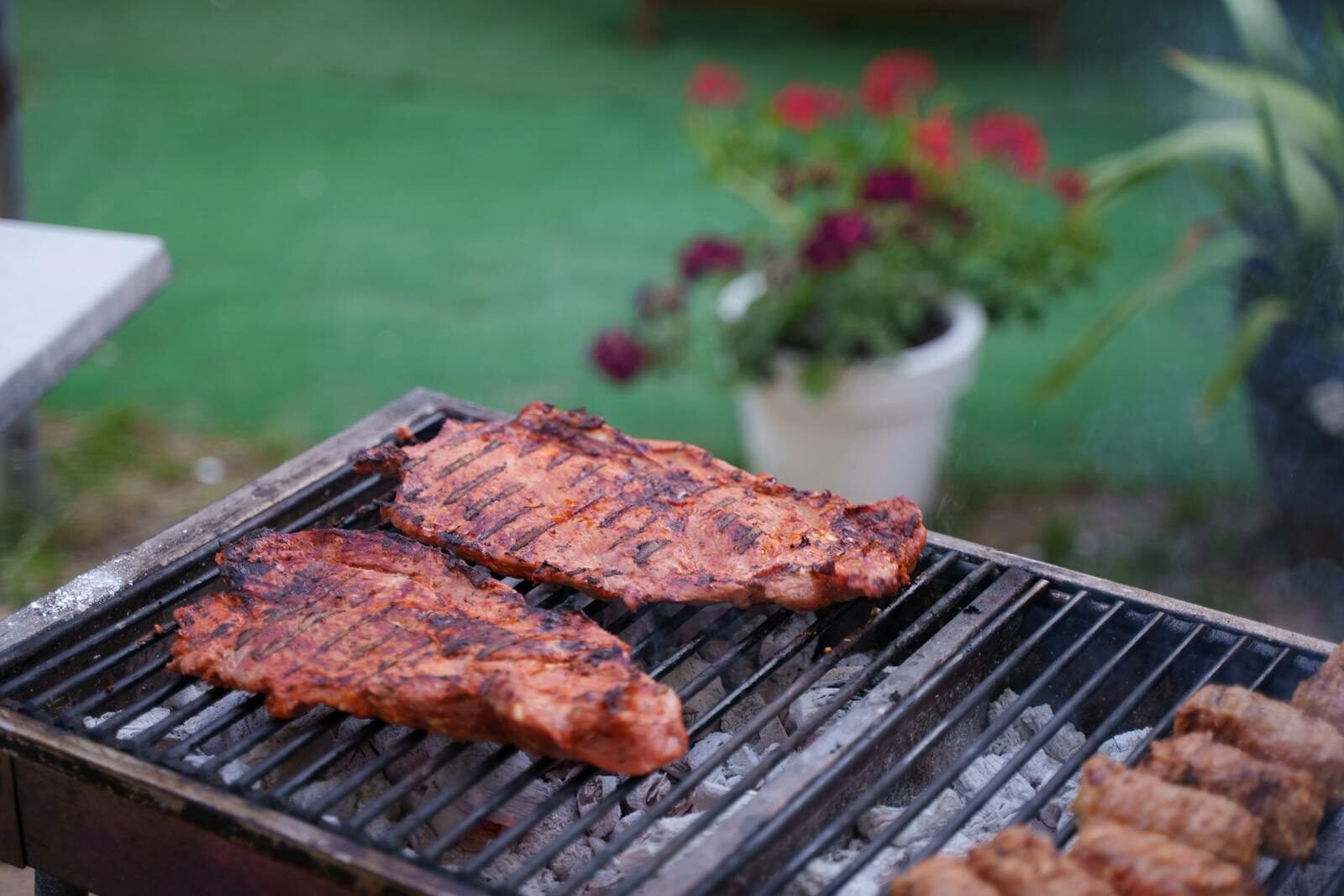 Juicy ribs sizzling on a charcoal grill in a garden setting. Perfect for summer BBQs.
