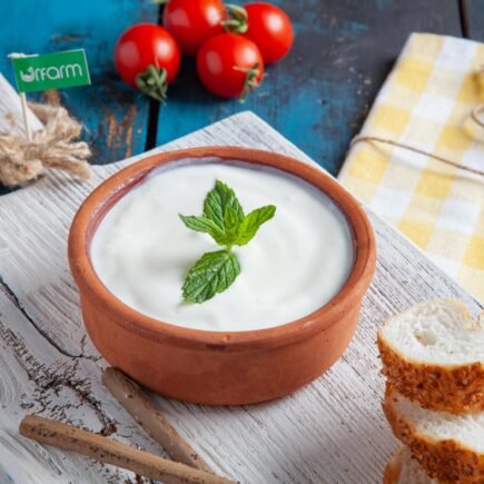 Descubra o Mundo do Iogurte: Um Alimento Versátil e Nutritivo Authentic Turkish yogurt served in a clay bowl with mint, tomatoes, and sesame bread on rustic wooden board.