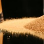 Receita de Sal Dourado para Temperar Seus Pratos a pile of sand next to a glass of beer