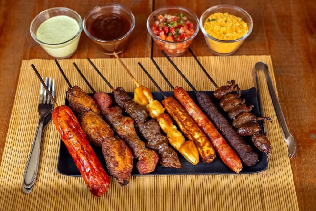 A variety of barbecued skewers with dips on a wooden table, perfect for outdoor dining.